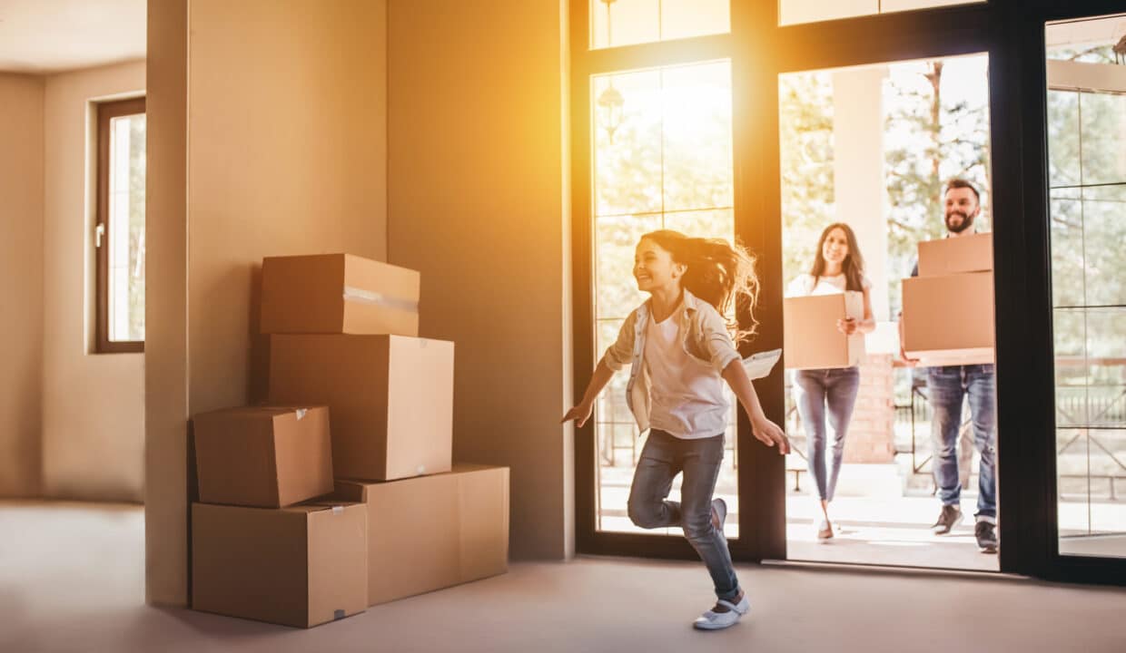 La famiglia si trasferisce nella nuova casa. Famiglia felice con scatole di cartone nella nuova casa il giorno del trasloco.